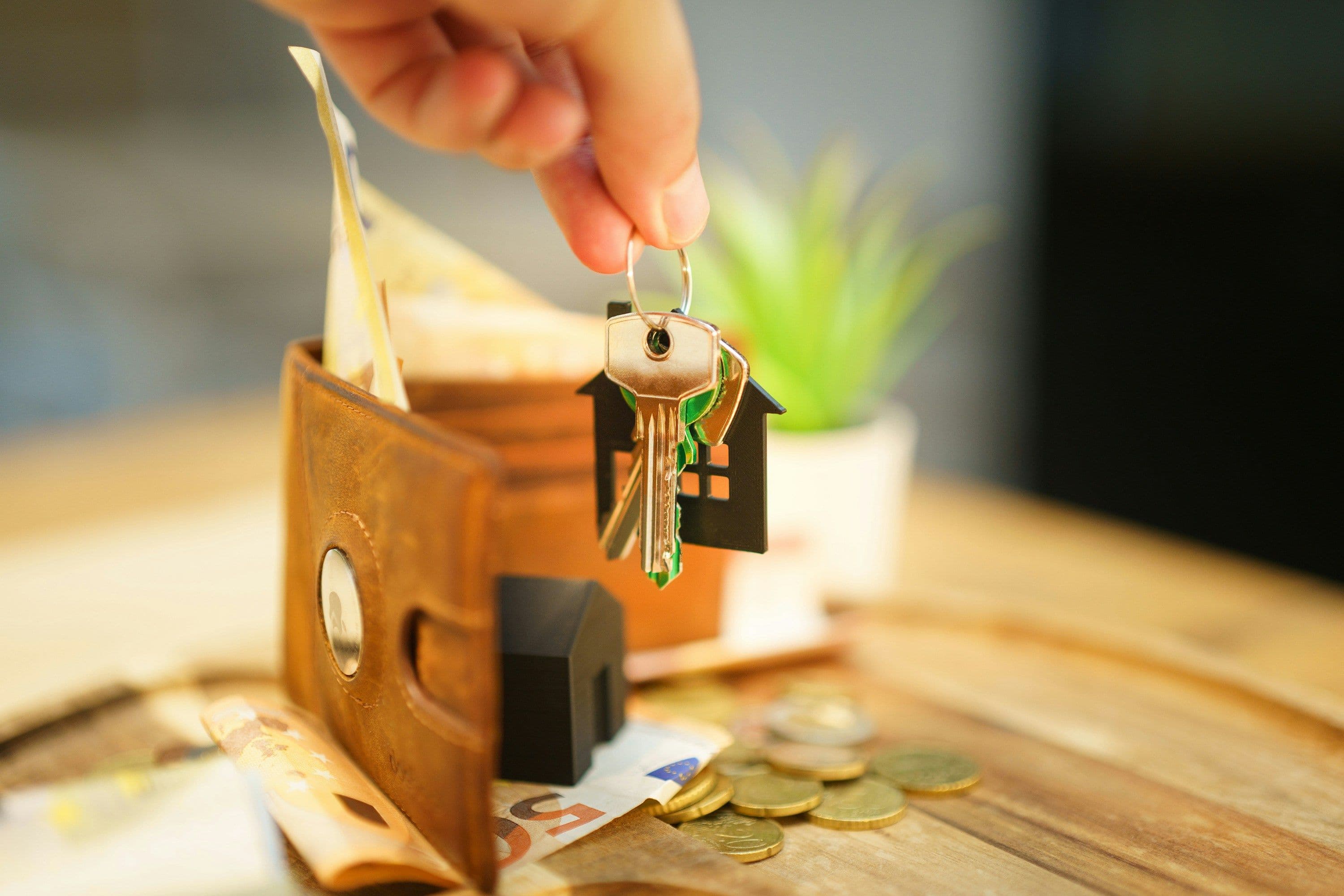 Wallet with keys and home representing trying to sell a home.